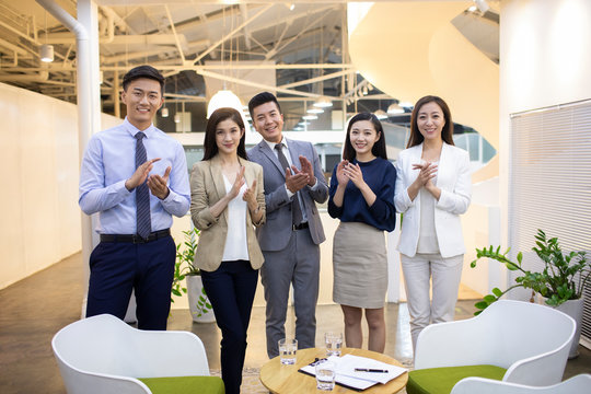Chinese business people clapping hands in office