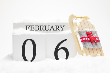 Wooden calendar for February, 6 th day of the winter month. The symbols of winter are snow and...