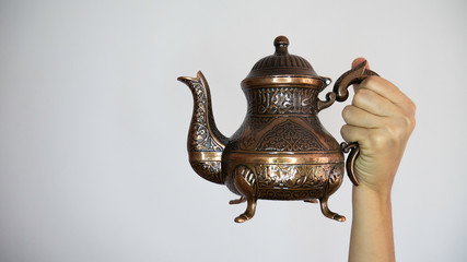 A woman's hand holds a Turkish teapot on a white background