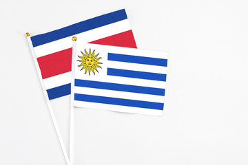 Uruguay and Costa Rica stick flags on white background. High quality fabric, miniature national flag. Peaceful global concept.White floor for copy space.