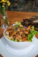 top veiw of Organic Ahi Tuna Poke Bowl with Rice and Veggies on wooden table on green background in cafe on terrace. Vertical shot