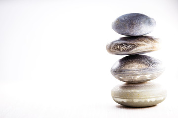 Pile of spa stones on the table against a white background, space for text. Zen stones for meditation and mystical healing.