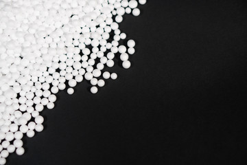 White Polystyrene foam beads on black background with copy space, waste cushioning material in...
