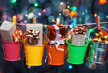 Christmas and New Year holidays background, gifts boxes in colored buckets on a background of garland lights
