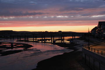 River Adur winds is way to the sea through Shoreham by Sea during a colourful sunset and reflection