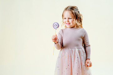 portrait of a beautiful little girl on a light background with a lollipop in hand. Food concept