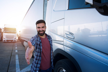 Truck drivers job openings. Middle aged professional trucker driver standing in front of his truck...