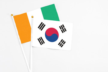 South Korea and Cote D'Ivoire stick flags on white background. High quality fabric, miniature national flag. Peaceful global concept.White floor for copy space.