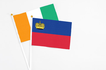 Liechtenstein and Cote D'Ivoire stick flags on white background. High quality fabric, miniature national flag. Peaceful global concept.White floor for copy space.