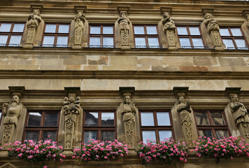 Building Windows and Statue Friezes on Stone Building with Purple Flowers in Wurzburg Germany