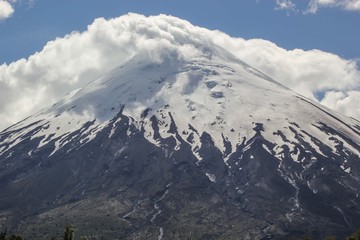 Fototapeta na wymiar volcan con nieve y nubes en la punta