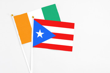 Puerto Rico and Cote D'Ivoire stick flags on white background. High quality fabric, miniature national flag. Peaceful global concept.White floor for copy space.