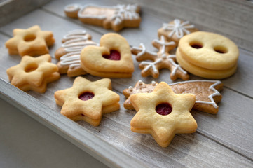 Christmas linzer sweets and gingerbread sweets, various shapes on gray wooden tray