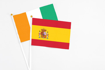 Spain and Cote D'Ivoire stick flags on white background. High quality fabric, miniature national flag. Peaceful global concept.White floor for copy space.