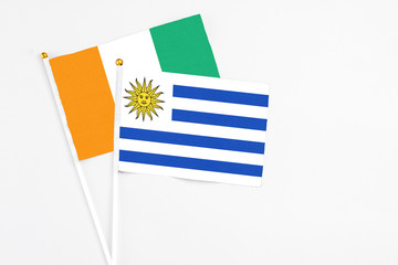 Uruguay and Cote D'Ivoire stick flags on white background. High quality fabric, miniature national...