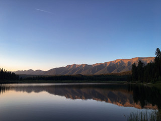 Mountain and forest reflection on lake at sunset