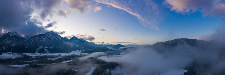 Obraz premium panorama of sunset mood at pinswang with snowy mountains, haze and clouds