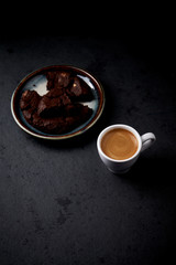 Cup of coffee and chocolate cookie on black stone background. Copy space.