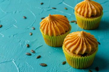 Pumpkin cupcakes with pumpkin-caramel cream on colorful Background