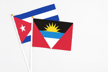 Antigua and Barbuda and Cuba stick flags on white background. High quality fabric, miniature national flag. Peaceful global concept.White floor for copy space.