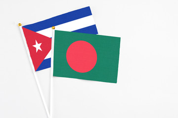 Bangladesh and Cuba stick flags on white background. High quality fabric, miniature national flag. Peaceful global concept.White floor for copy space.