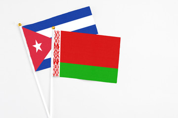 Belarus and Cuba stick flags on white background. High quality fabric, miniature national flag. Peaceful global concept.White floor for copy space.