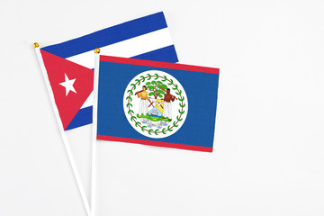 Belize and Cuba stick flags on white background. High quality fabric, miniature national flag. Peaceful global concept.White floor for copy space.
