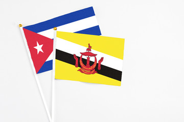 Brunei and Cuba stick flags on white background. High quality fabric, miniature national flag. Peaceful global concept.White floor for copy space.