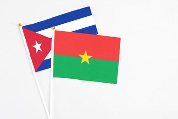 Burkina Faso and Cuba stick flags on white background. High quality fabric, miniature national flag. Peaceful global concept.White floor for copy space.