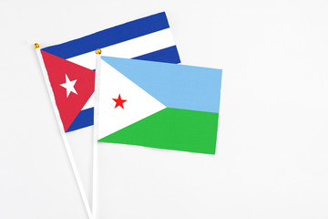Djibouti and Cuba stick flags on white background. High quality fabric, miniature national flag. Peaceful global concept.White floor for copy space.