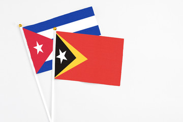 East Timor and Cuba stick flags on white background. High quality fabric, miniature national flag. Peaceful global concept.White floor for copy space.
