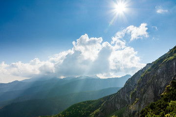 Mountain green vegetation and forests. Polish Tatras. The sun from behind the clouds. Place for text