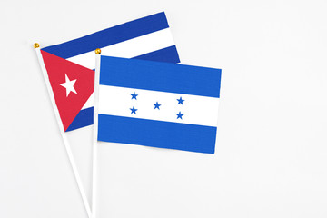 Honduras and Cuba stick flags on white background. High quality fabric, miniature national flag. Peaceful global concept.White floor for copy space.