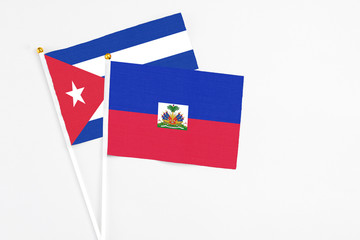 Haiti and Cuba stick flags on white background. High quality fabric, miniature national flag. Peaceful global concept.White floor for copy space.