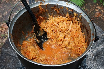 Braised cabbage cooked in a large pot on a fire in the forest
