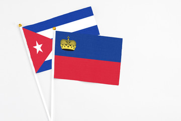 Liechtenstein and Cuba stick flags on white background. High quality fabric, miniature national flag. Peaceful global concept.White floor for copy space.