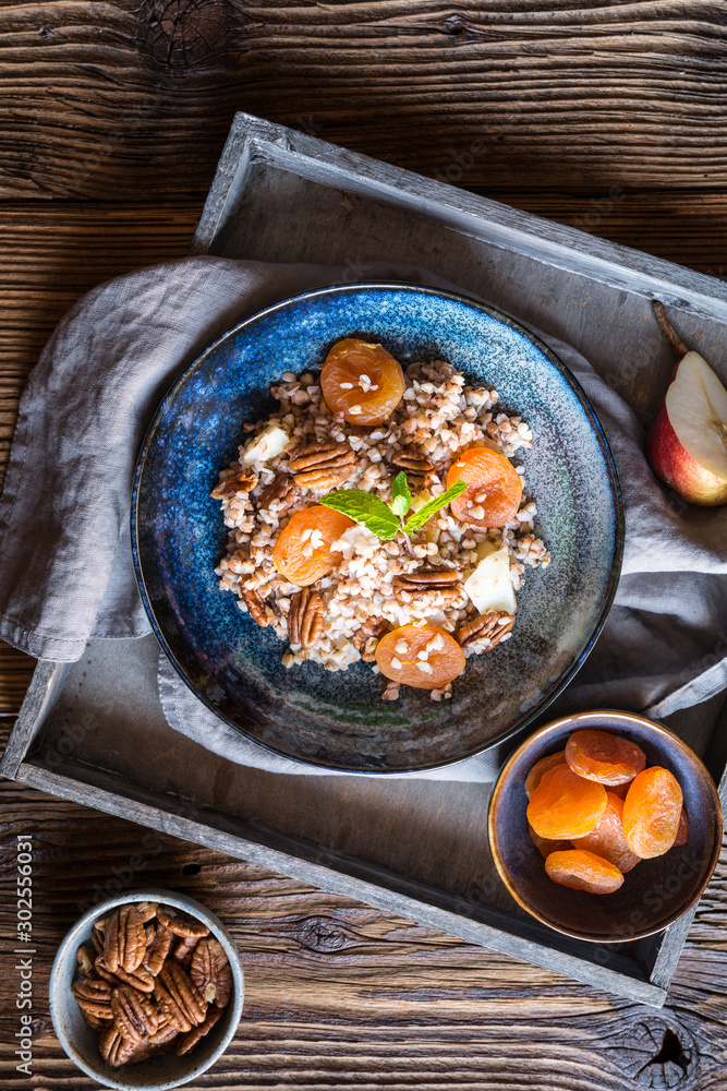 Wall mural Vegan buckwheat salad with dried apricot, pear and pecan nuts