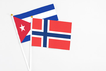 Norway and Cuba stick flags on white background. High quality fabric, miniature national flag. Peaceful global concept.White floor for copy space.