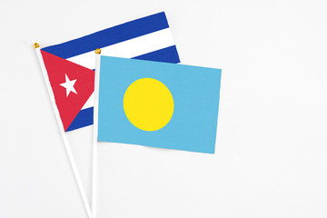 Palau and Cuba stick flags on white background. High quality fabric, miniature national flag. Peaceful global concept.White floor for copy space.