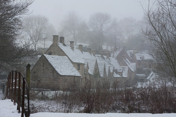 Cold village in the cotswolds with snow on the ground and mist