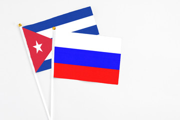 Russia and Cuba stick flags on white background. High quality fabric, miniature national flag. Peaceful global concept.White floor for copy space.
