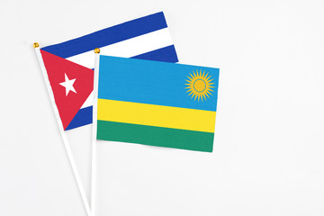 Rwanda and Cuba stick flags on white background. High quality fabric, miniature national flag. Peaceful global concept.White floor for copy space.