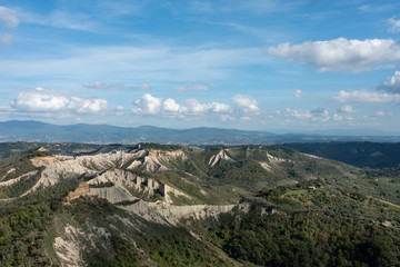 Tuscany landscape view from Civita di Bagnoregio, Italy. Cliffs under blue sky. 