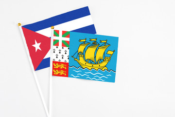 Saint Pierre And Miquelon and Cuba stick flags on white background. High quality fabric, miniature national flag. Peaceful global concept.White floor for copy space.