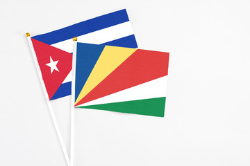 Seychelles and Cuba stick flags on white background. High quality fabric, miniature national flag. Peaceful global concept.White floor for copy space.
