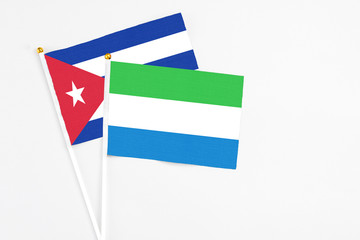 Sierra Leone and Cuba stick flags on white background. High quality fabric, miniature national flag. Peaceful global concept.White floor for copy space.