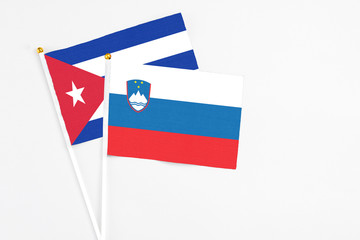 Slovenia and Cuba stick flags on white background. High quality fabric, miniature national flag. Peaceful global concept.White floor for copy space.