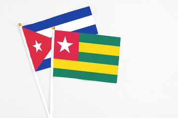 Togo and Cuba stick flags on white background. High quality fabric, miniature national flag. Peaceful global concept.White floor for copy space.