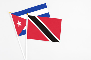 Trinidad And Tobago and Cuba stick flags on white background. High quality fabric, miniature national flag. Peaceful global concept.White floor for copy space.