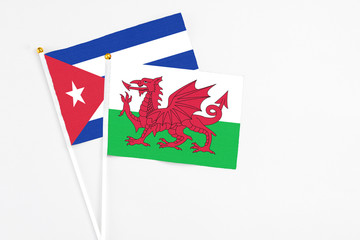 Wales and Cuba stick flags on white background. High quality fabric, miniature national flag. Peaceful global concept.White floor for copy space.